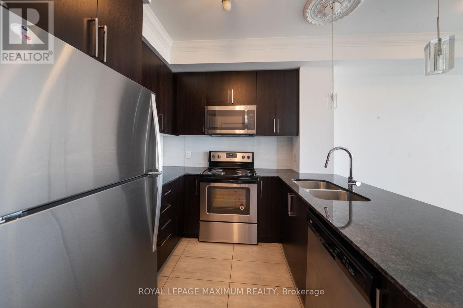 A modern kitchen with dark wood cabinets and stainless steel appliances.