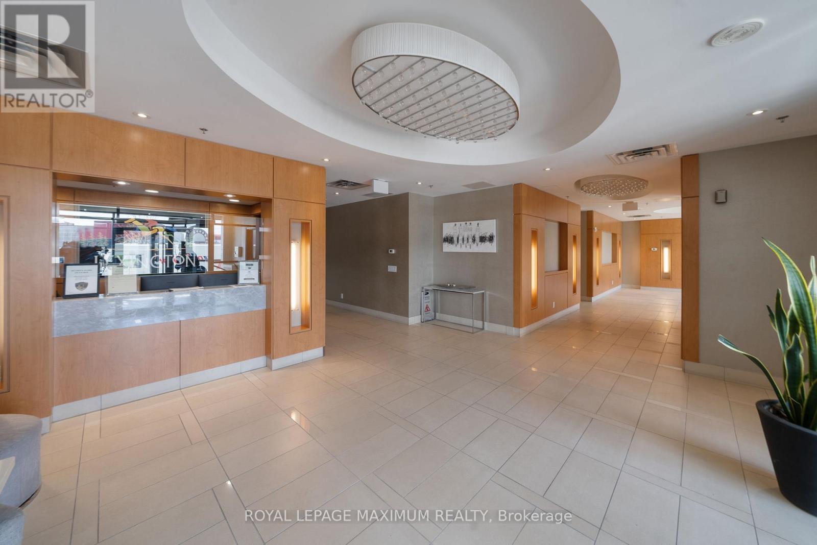 A spacious office lobby with a reception desk and a potted plant.