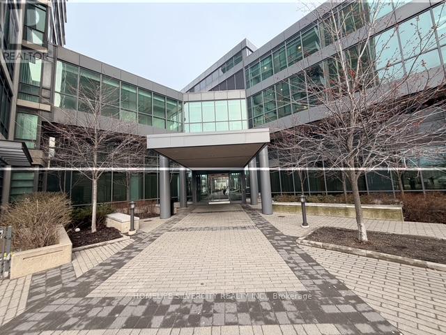 A modern building with a glass facade and a covered walkway leading to the entrance.