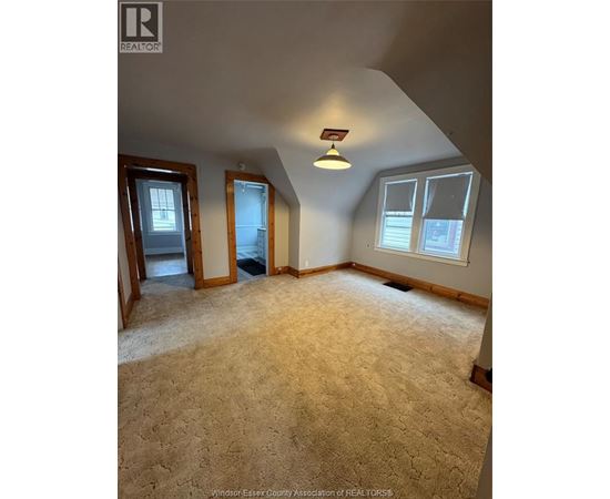 A carpeted room with a skylight and a window.