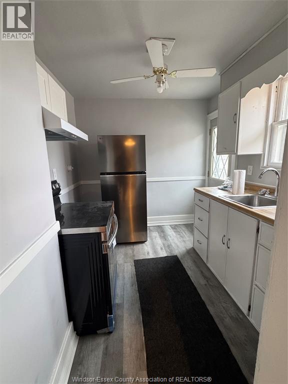 A kitchen with a stainless steel refrigerator and wooden floors.