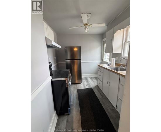 A kitchen with a stainless steel refrigerator and wooden floors.