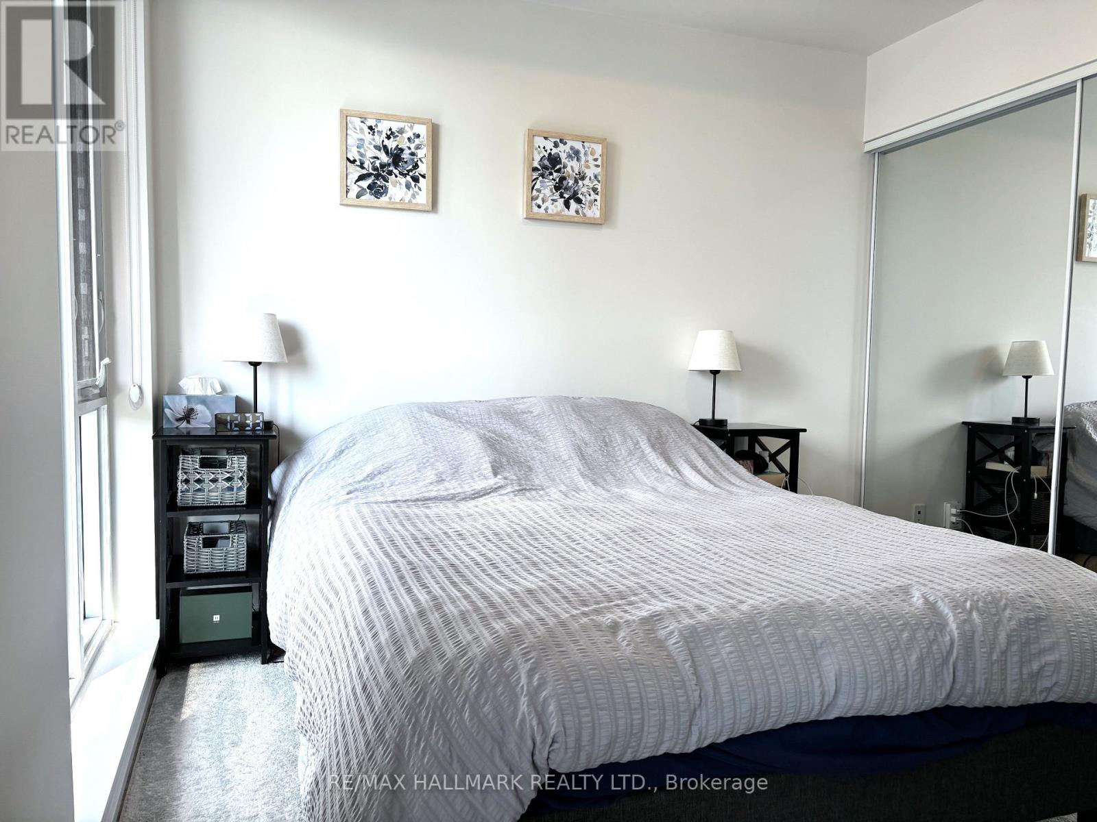 A bedroom with a bed, nightstands, and two wall lamps.