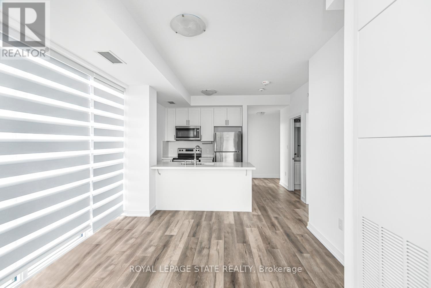 A modern kitchen with white cabinets and a wooden floor.