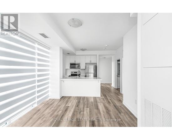 A modern kitchen with white cabinets and a wooden floor.
