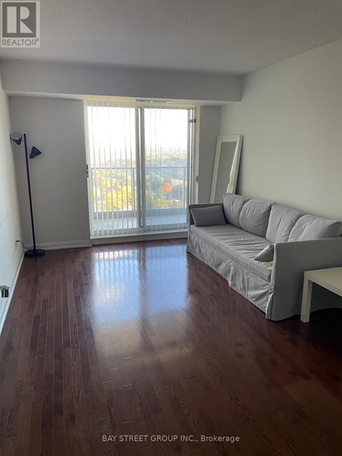 A living room with a grey couch and a wooden floor.