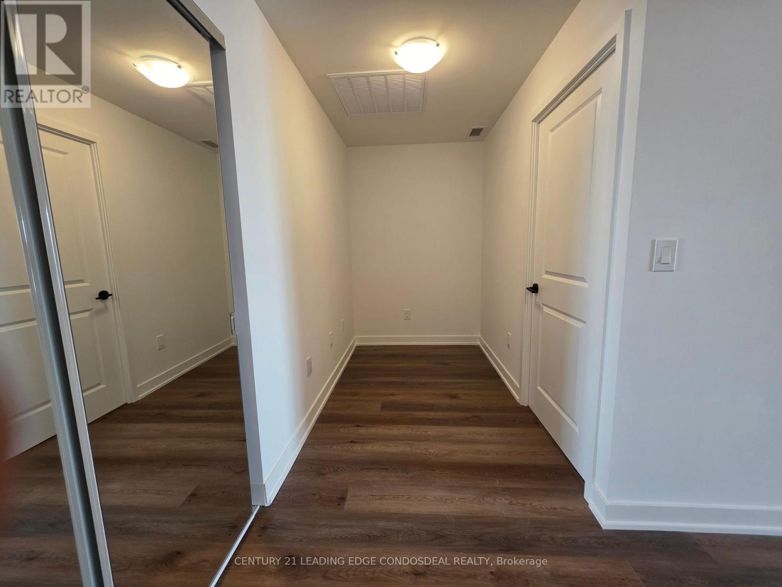 A hallway with wood floors and white walls.