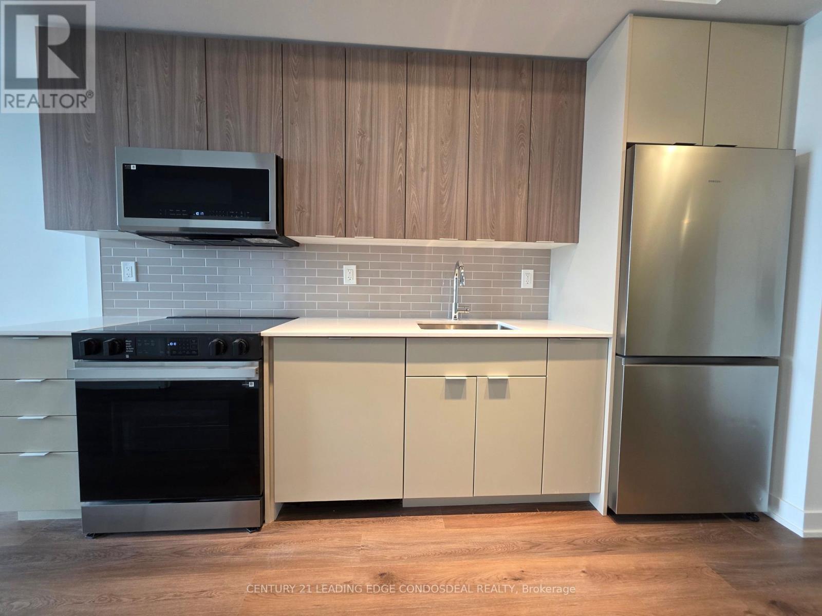 A kitchen with wooden cabinets and a stainless steel refrigerator.