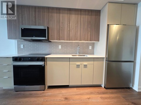 A kitchen with wooden cabinets and a stainless steel refrigerator.