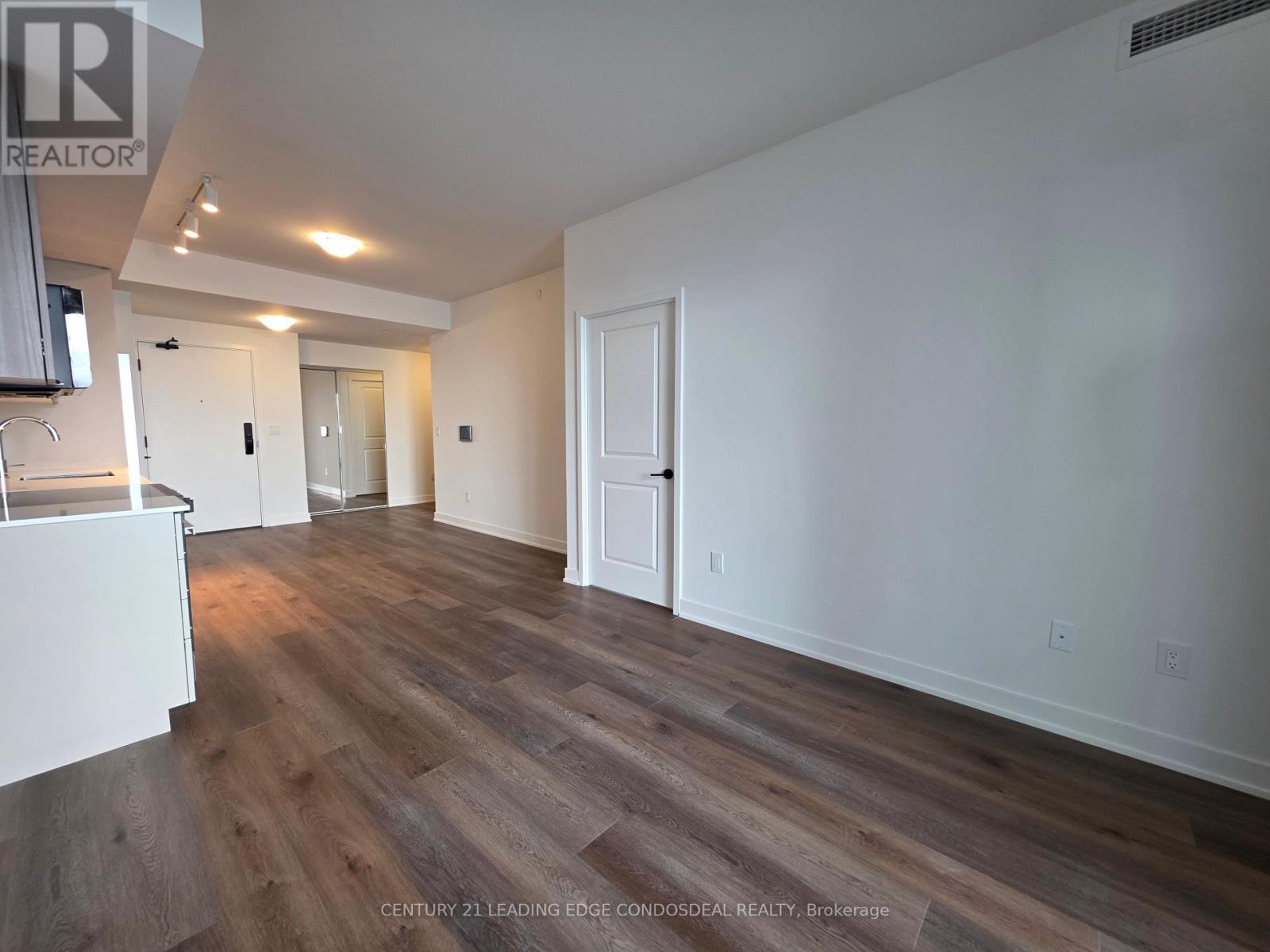 A spacious room with wooden flooring and white walls.