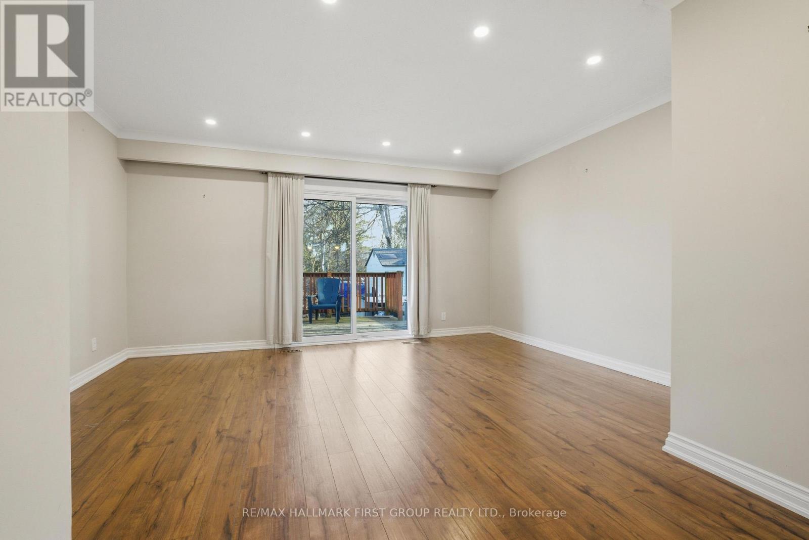 A spacious room with wooden flooring and a sliding glass door leading to a balcony.