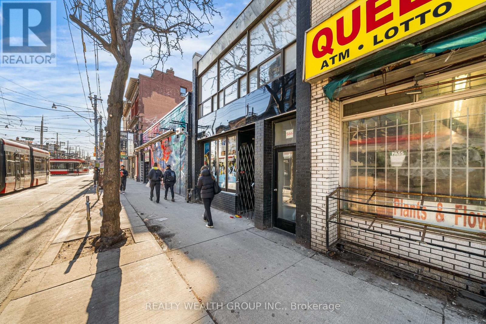 A street view with a Quee Lotto sign on a building.