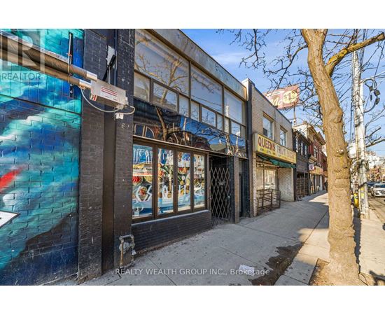 A street view of a building with a mural on the side and a tree in front.