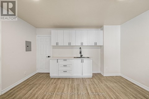 A white kitchen with wooden floors and cabinets.
