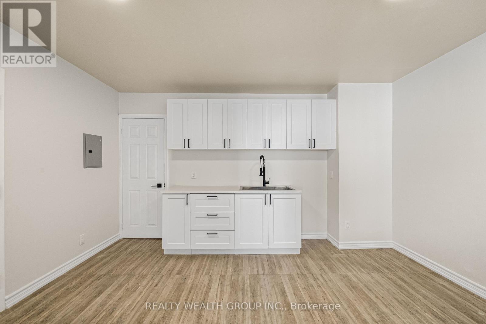 A white kitchen with wooden floors and cabinets.