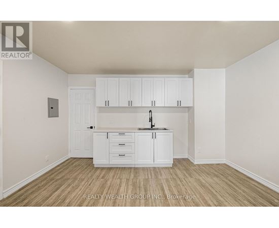 A white kitchen with wooden floors and cabinets.