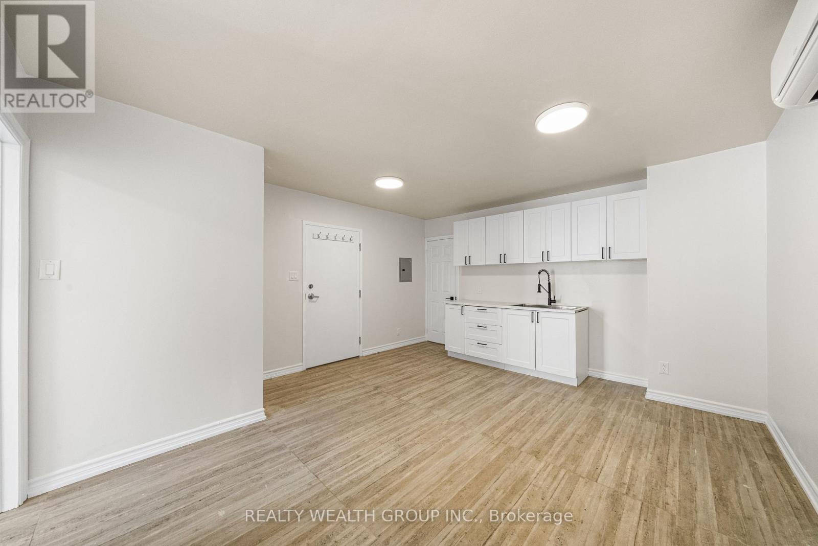A white room with wooden flooring and a large white cabinet.