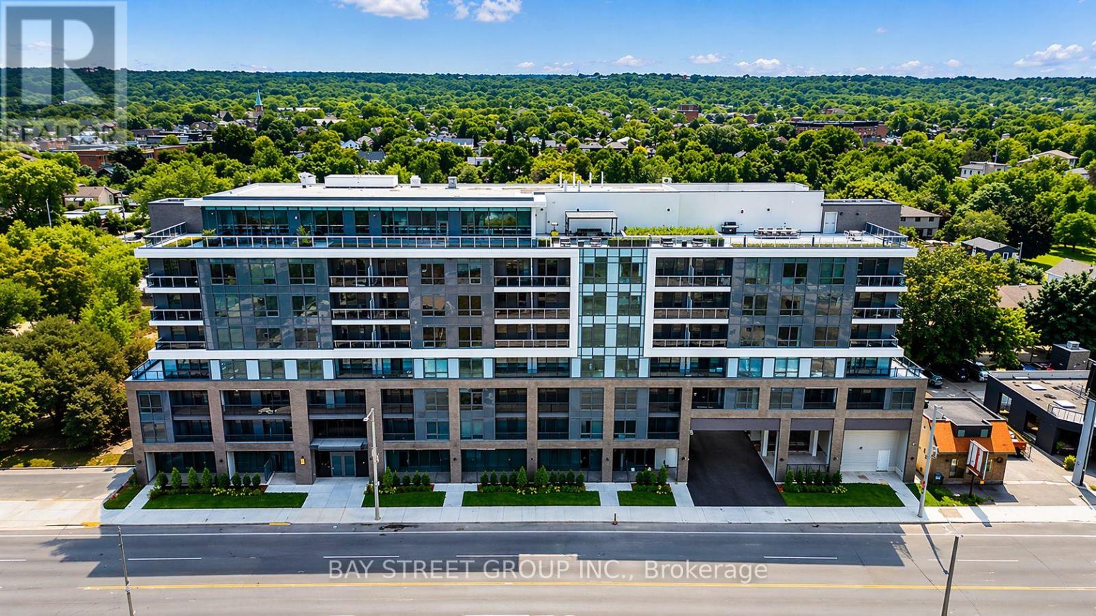 A modern multi-story building with a green roof and a parking lot in front.