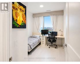 A bedroom with a bed, desk, and a painting of an owl.