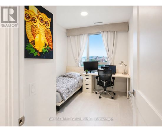 A bedroom with a bed, desk, and a painting of an owl.