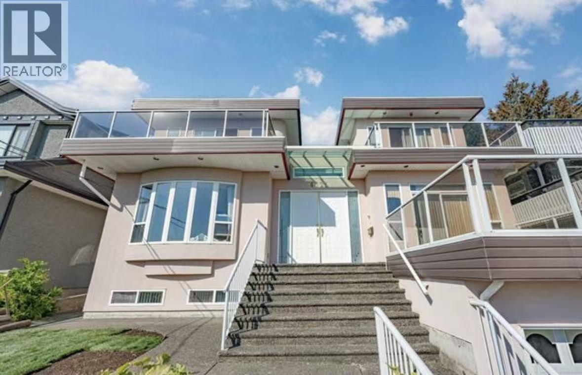 A modern house with a glass balcony and stairs leading to the entrance.