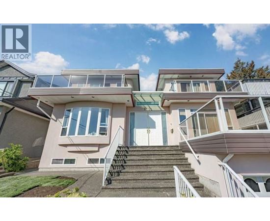 A modern house with a glass balcony and stairs leading to the entrance.