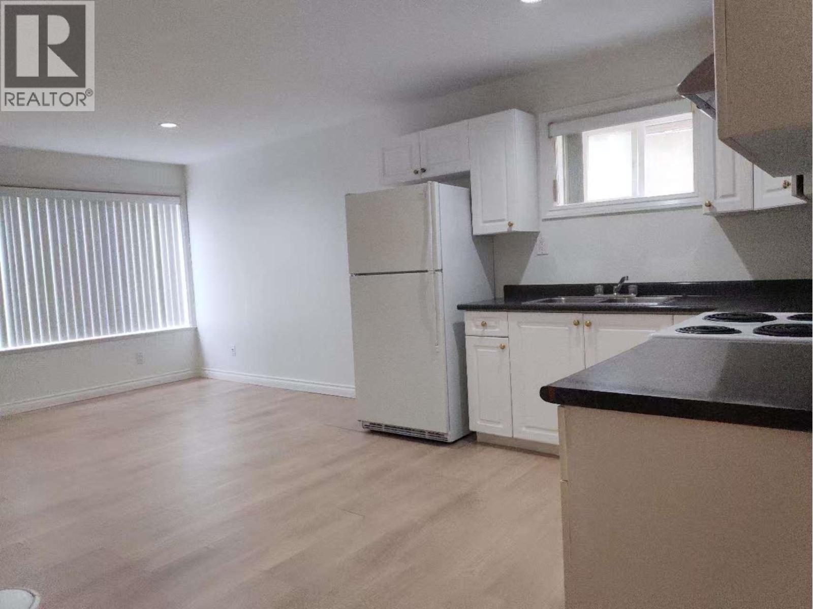 A kitchen with a refrigerator, cabinets, and a countertop.