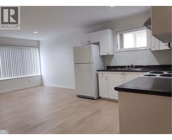 A kitchen with a refrigerator, cabinets, and a countertop.