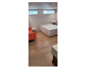 A bedroom with a bed, a chair, and a table.