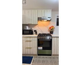 A modern kitchen with a black stove top oven and a microwave on the counter.