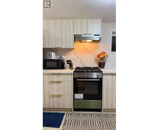 A modern kitchen with a black stove top oven and a microwave on the counter.