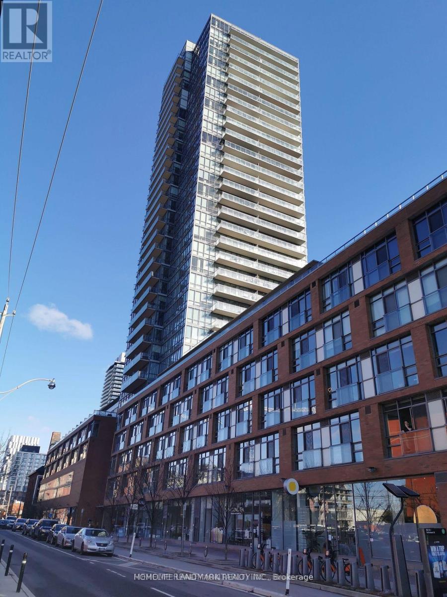 A tall building with a striped facade stands next to a shorter building with a brick facade.