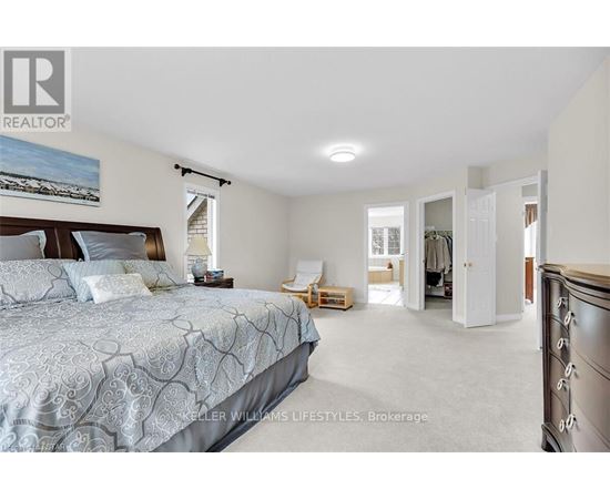 A bedroom with a large bed and a painting on the wall.