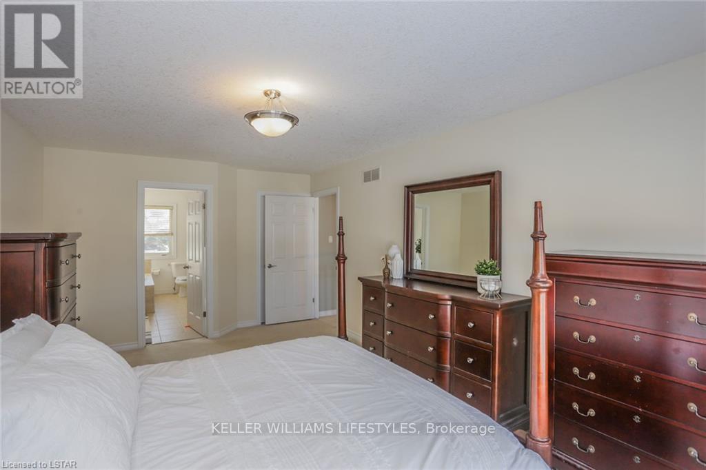 A bedroom with a white bed and a wooden dresser.