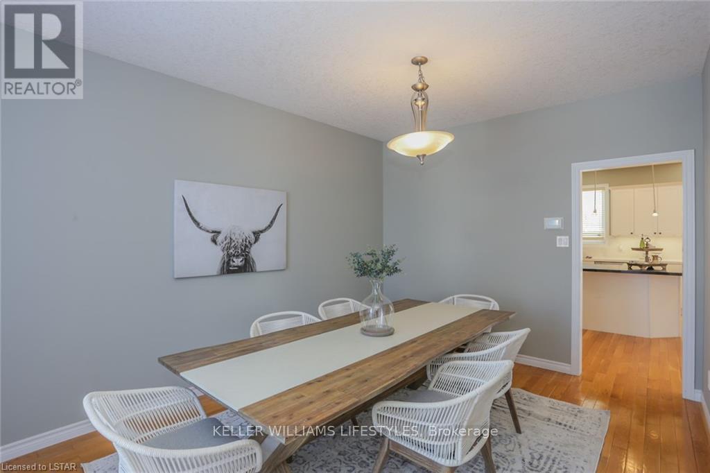 A dining room with a wooden table and white chairs.