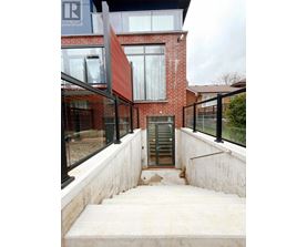 A red brick house with a glass door and a staircase leading to it.