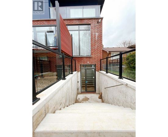 A red brick house with a glass door and a staircase leading to it.