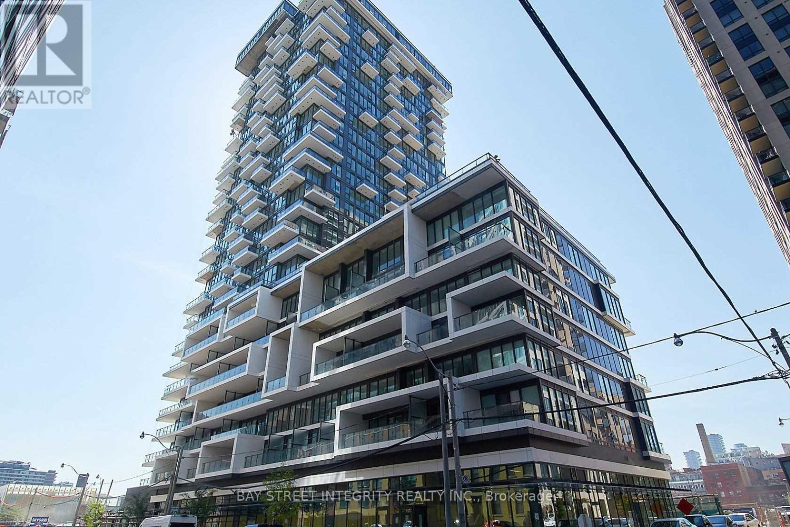 A tall building with a glass facade stands in front of a street light.