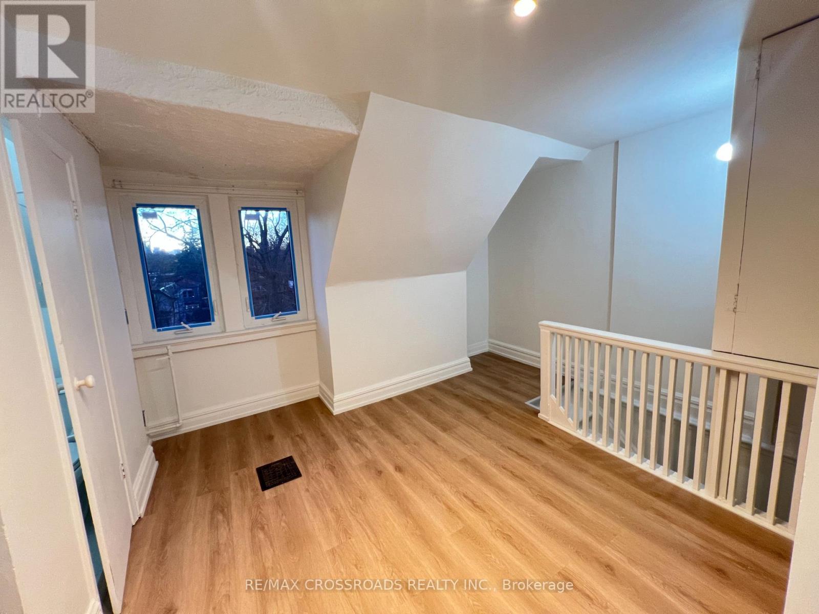 A room with wooden floors and white walls, with a window and a door visible.