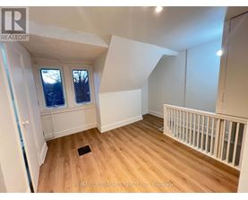 A room with wooden floors and white walls, with a window and a door visible.