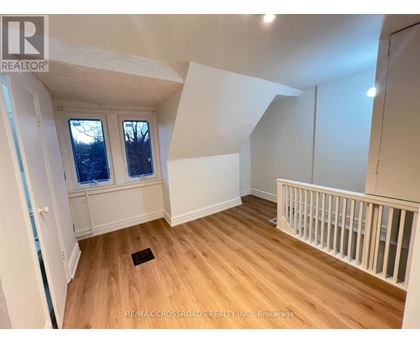 A room with wooden floors and white walls, with a window and a door visible.