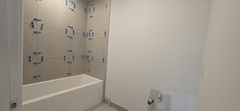 A bathroom under construction with blue tape on the walls.
