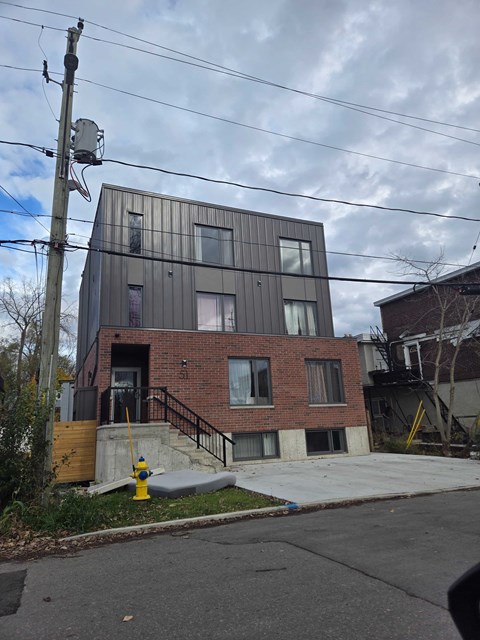 A modern building with a brick facade and a fire hydrant in front.