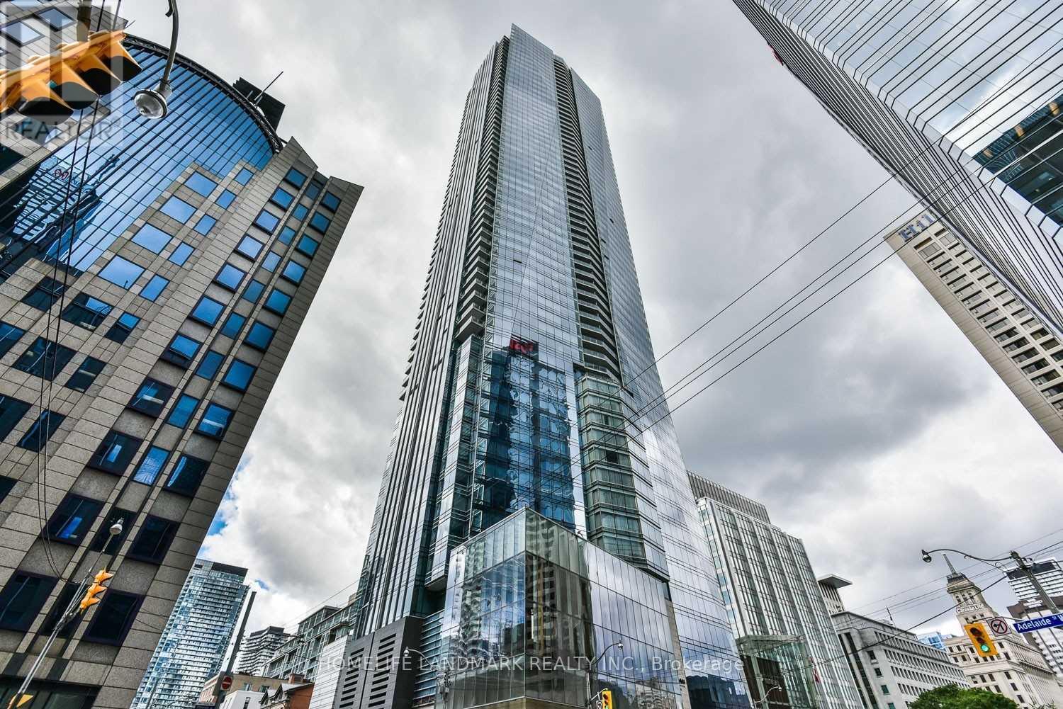 A tall glass skyscraper stands in the middle of a cityscape.