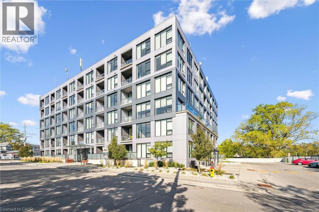 A modern multi-story building with a glass facade and a parking lot in front.