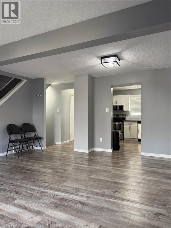A room with a wooden floor and a kitchen in the background.