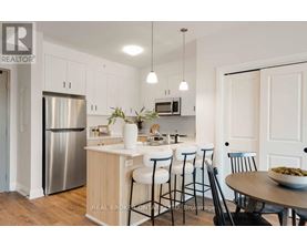 A modern kitchen with a stainless steel refrigerator and white cabinets.