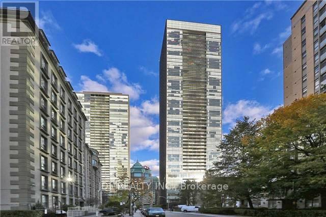 A city street with a tall building in the middle and a shorter building to the left.