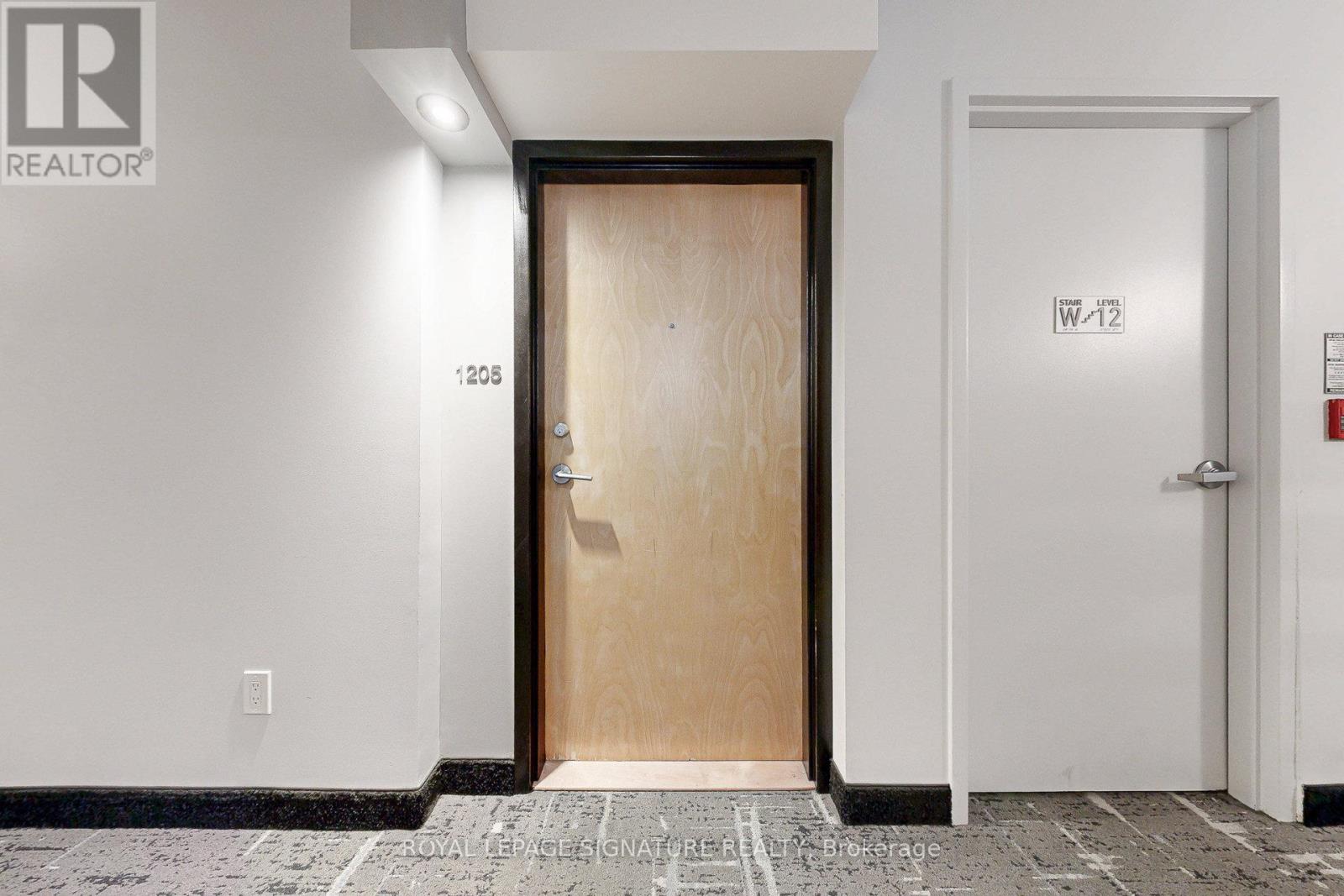 A white hallway with a wooden door and a white door on the right.