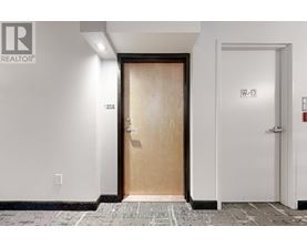 A white hallway with a wooden door and a white door on the right.